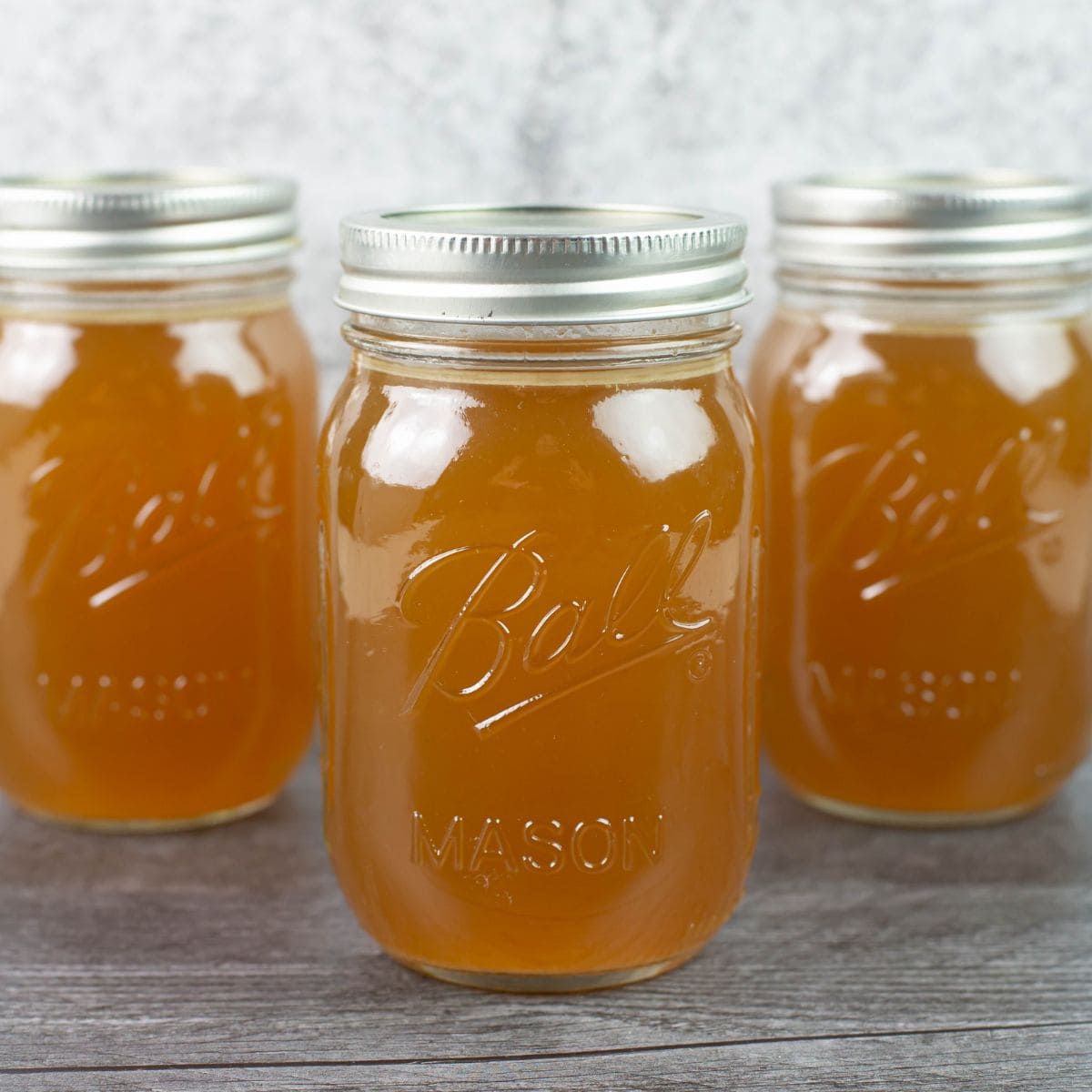 Homemade turkey broth in three large mason jars.