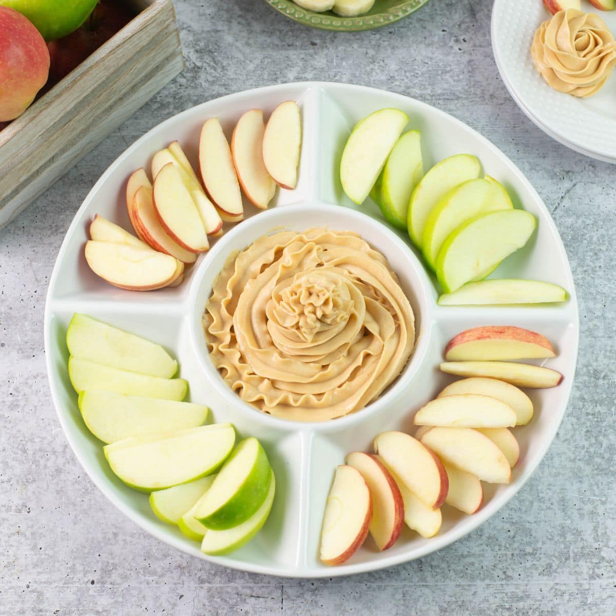 Peanut Butter Dip in the center of sliced apples in a round serving tray.