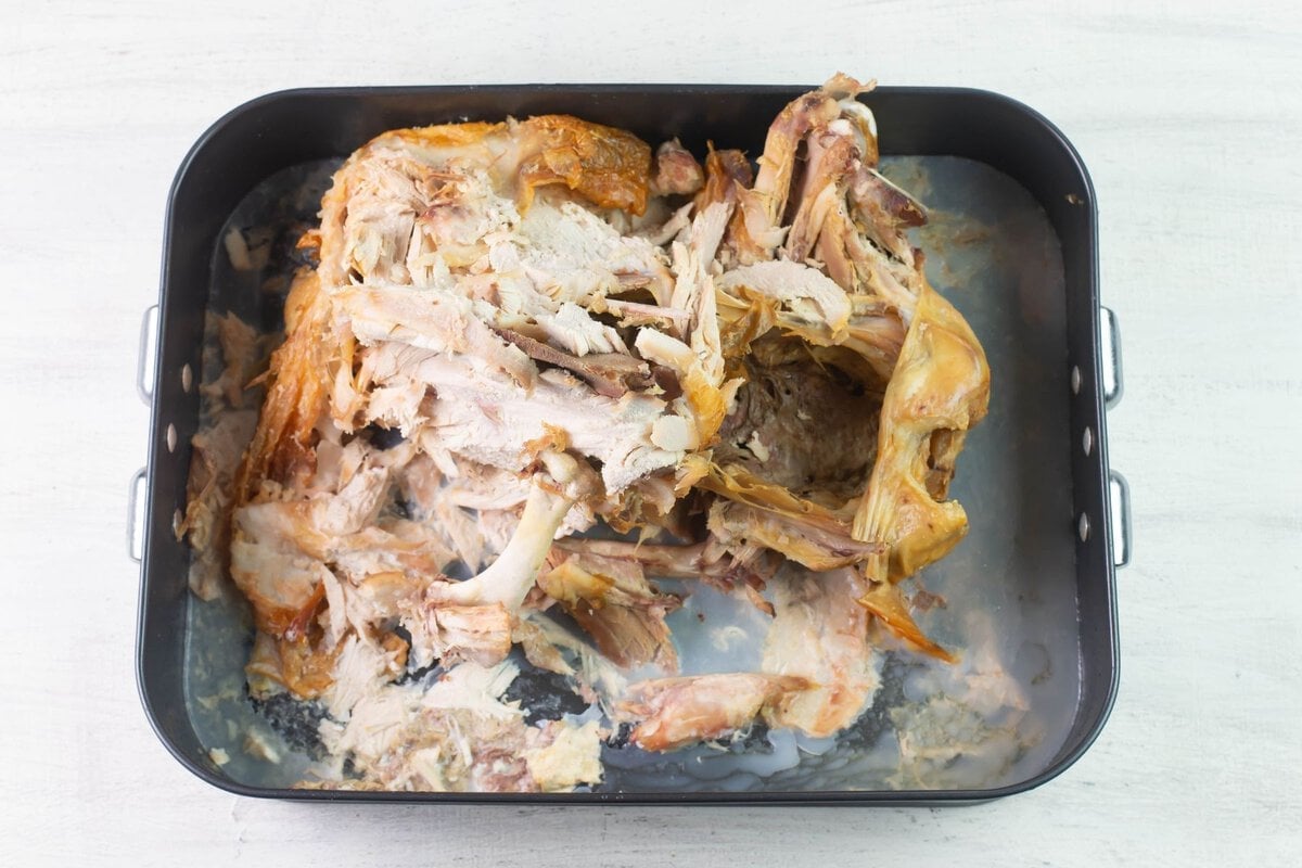 Leftover turkey bones and scraps in a roasting pan.