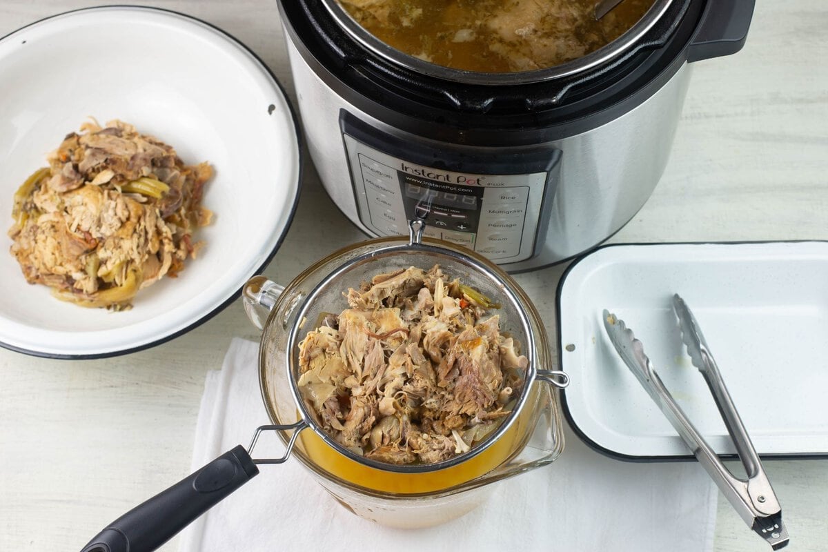 Straining the solids from the broth with a fine strainer.