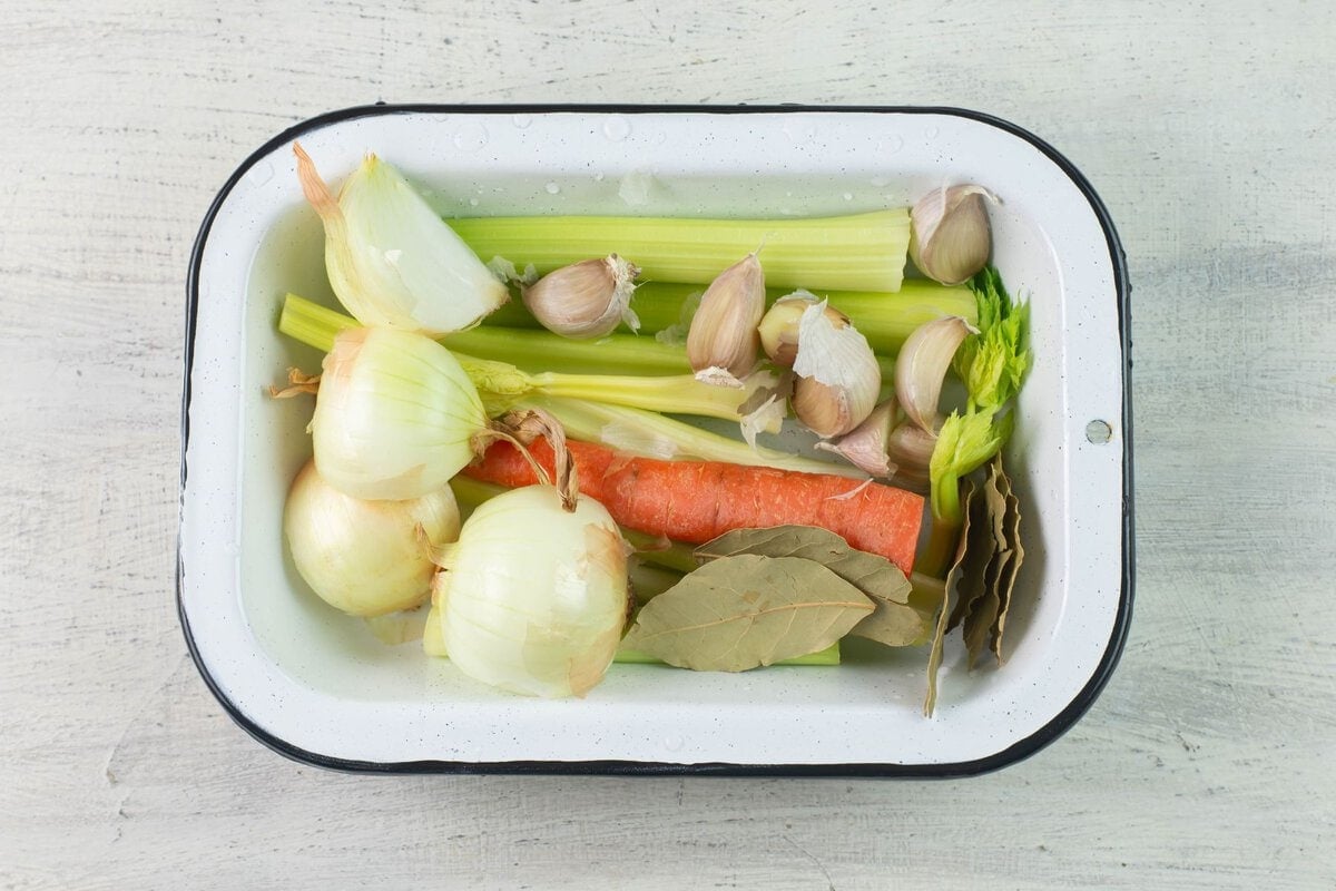 Vegetables and herbs for broth in a enamel pan.